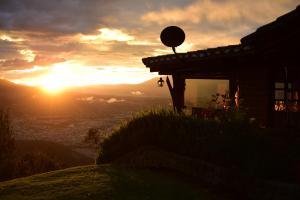 um pôr-do-sol no topo de uma colina com uma casa em La Estelita em Ibarra