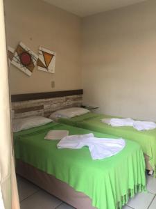 two beds in a room with green sheets and towels at Pousada Coco Verde Natal in Natal