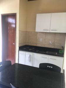 a kitchen with a black table and white appliances at Pousada Coco Verde Natal in Natal