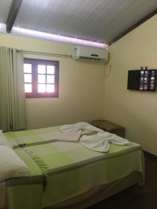 Un dormitorio con una cama con sábanas verdes y una ventana en Pousada Coco Verde Natal, en Natal