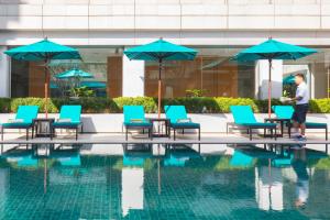 
a patio area with chairs, tables and umbrellas at Holiday Inn Bangkok, an IHG Hotel in Bangkok
