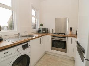 a white kitchen with a sink and a washer at Lovatt House Apartment Tynemouth in North Shields +16 photos