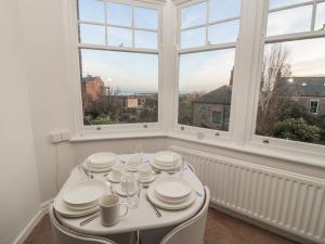 a white dining room with a table and windows at Lovatt House Apartment Tynemouth in North Shields