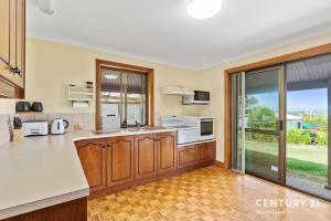 a kitchen with wooden cabinets and a large window at Reef & Vines - Port Noarlunga - C21 SouthCoast Holidays in Port Noarlunga
