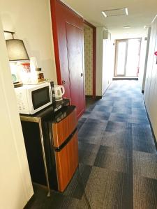 a hallway of a hotel room with a microwave and refrigerator at Hotel Unicorn in Nagano