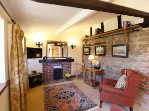 a living room with a fireplace and a brick wall at Elephant Cottage in Edwin Loach
