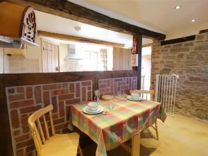 Elephant Cottage في Edwin Loach: غرفة طعام مع طاولة وكراسي وجدار من الطوب