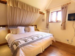 a bedroom with a large white bed with a window at Elephant Cottage in Edwin Loach