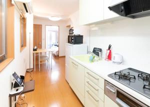 une cuisine avec des armoires blanches et un four à plaques de cuisson dans l'établissement Yahiro 4-chome House 1F, à Tokyo