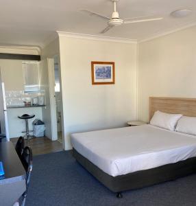 1 dormitorio con cama blanca, mesa y techo en Hervey Bay Motel en Hervey Bay