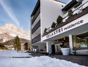 una persona caminando fuera de un edificio en la nieve en Residence Lastei, en San Martino di Castrozza