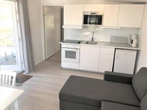 cocina con armarios blancos y sala de estar con sofá en Trelleborg Strand, en Trelleborg