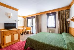 a bedroom with a green bed and a television at Residence Lastei in San Martino di Castrozza