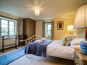a bedroom with a bed and a table and windows at Elm View in Chipping Campden