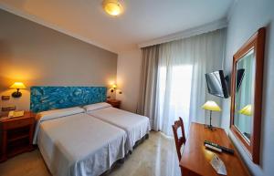 a bedroom with a bed and a desk and a television at Hotel Bajamar Centro in Nerja