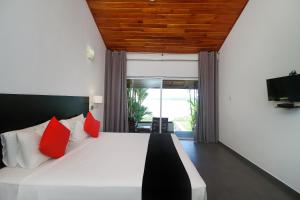 a bedroom with a large white bed with red pillows at Kalla Bongo Lake Resort in Hikkaduwa