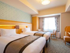 神戸市にあるホテルモントレ神戸のベッド3台と窓が備わるホテルルームです。