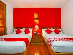 duas camas num quarto com paredes vermelhas em OYO Posada De Los Angeles, Pátzcuaro em Pátzcuaro