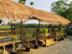 Bussaracum Resort في مدينة كانشانابوري: كوخ كبير من القش مع مقاعد ونباتات خزف