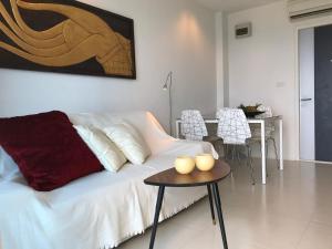 een woonkamer met een witte bank en een tafel bij GrandBlue Condominium Mae Phim TOP FLOOR WITH SEA VIEW 706 in Mae Pim