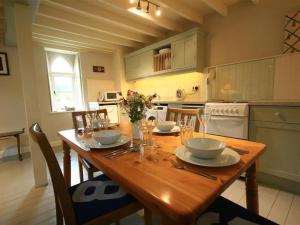 una cocina con una mesa de madera con platos y vasos. en Cider Press Cottage en Priston