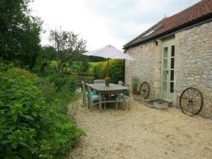 einen Tisch und Stühle mit Sonnenschirm im Hof in der Unterkunft Cider Press Cottage in Priston