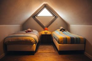 a attic bedroom with two beds and a window at Residentie Duindoorn in Koksijde