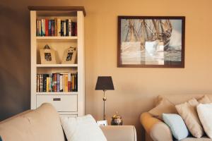 a living room with a couch and a book shelf with books at Residentie Duindoorn in Koksijde
