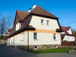 ein großes weißes Haus mit braunem Dach in der Unterkunft Apartmány Rychtaříkovi in Černý Důl