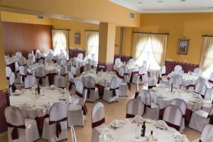un salón de banquetes con mesas y sillas blancas en Hotel Romerito en Málaga