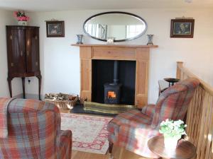 a living room with a fireplace and two chairs and a mirror at The Folly at Castlebridge in Mere