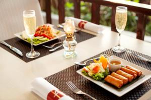 a table with two plates of food and two glasses of champagne at Sunwing Kamala Beach - SHA Plus in Kamala Beach
