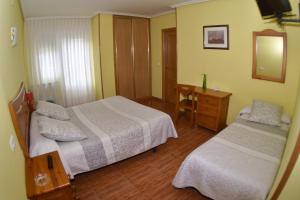 a bedroom with two beds and a table and a mirror at Montaña Palentina in Guardo