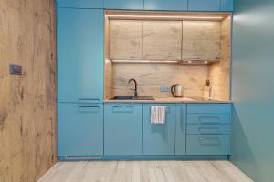a kitchen with blue cabinets and a sink at Apartamenty Rondo in Świnoujście +291 photos