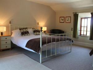 a bedroom with a large bed and a chair at Little Millend in Coleford