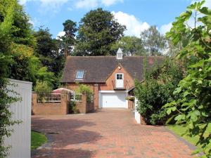 a brick house with a white garage and a driveway at Granary Cottage in Royal Tunbridge Wells