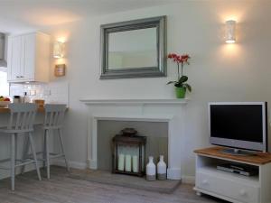 a living room with a television and a fireplace at Granary Cottage in Royal Tunbridge Wells