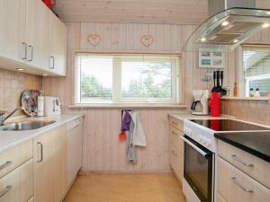 een keuken met witte kasten, een wastafel en een raam bij 7 person holiday home in Hj rring in Hjørring