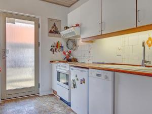 グドイェムにある4 person holiday home in Gudhjemの白いキャビネットと白い食器洗い機付きのキッチンが備わります。