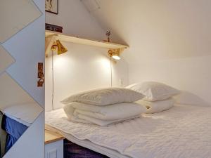 een bed met witte lakens en kussens in een kamer bij 4 person holiday home in Gudhjem in Gudhjem