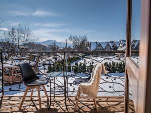einen Balkon mit zwei Stühlen und einem Tisch mit Schnee darauf in der Unterkunft DOMKI GALANTÓWKA in Zakopane
