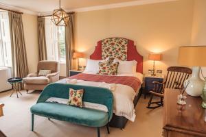 a bedroom with a large bed and a chair at Tay House in Dunkeld