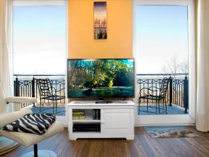 a living room with a flat screen tv and two windows at App Seaside in Insel Poel