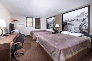 a hotel room with two beds and a desk at Super 8 by Wyndham Bismarck in Bismarck