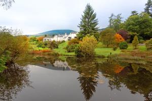 Blick auf einen See mit einem Haus und Bäumen in der Unterkunft Macdonald Forest Hills Resort in Aberfoyle