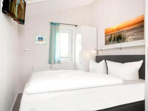 a white bedroom with a large white bed and a window at Dänische Ferienhäuser am Salzhaff Haus Strandbrise in Malchow