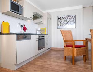 a kitchen with white cabinets and a table and a chair at Einhusen Kornkammer in Einhusen