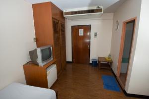 a hotel room with a tv and a bed at Muangphol Mansion in Bangkok