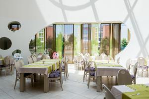 a dining room with tables and chairs and windows at Aqua Nevis Hotel & Aqua Park - All Inclusive in Sunny Beach