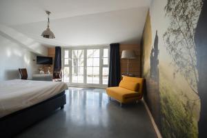 a bedroom with a bed and a yellow chair at Posthoorn Lodge in Woerden